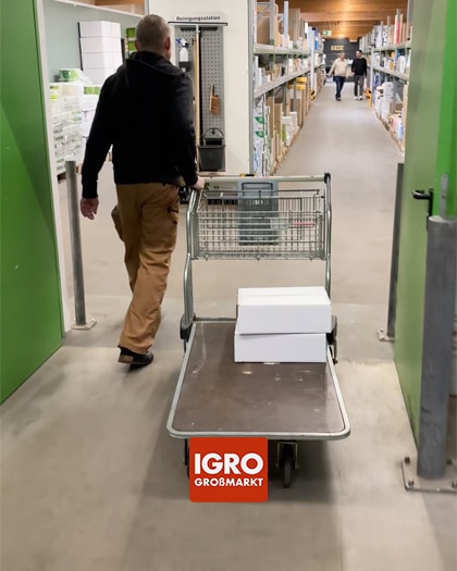 Ein Kunde schiebt einen Einkaufswagen im IGRO Großmarkt Norden durch die Gänge. Das IGRO Logo ist auf dem Wagen platziert.