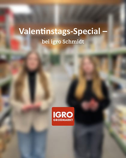 Hochformatiges Bild im Lagergang des IGRO Großmarkts Aurich mit zwei unscharf dargestellten Mitarbeiterinnen. Oben Text: "Valentinstags-Special – bei igro Schmidt". Im Vordergrund das IGRO GROSSMARKT Logo.