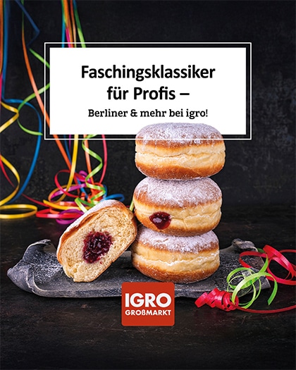 Faschingsklassiker bei IGRO: Drei frische Berliner mit Puderzucker auf einer Schieferplatte, einer davon ist aufgeschnitten und zeigt die Marmeladenfüllung. Im Hintergrund bunte Luftschlangen.